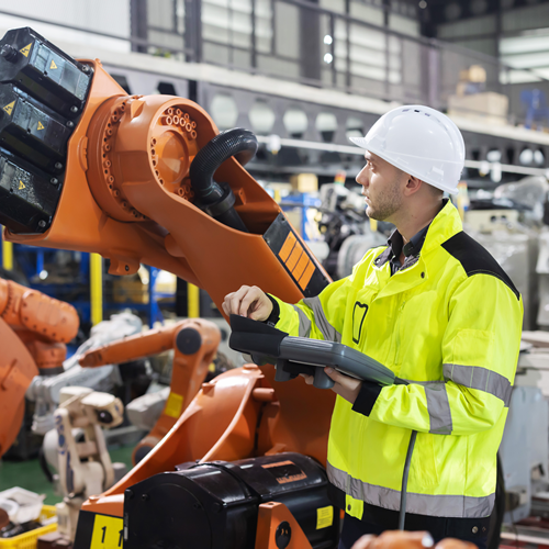 Trabajador manejando el brazo de un robot industrial en una fábrica